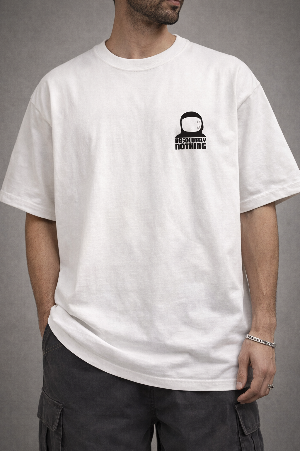 A model from the apparel brand Absolutely Nothing wearing a white oversized t-shirt with a graphic design and text on the front that has the astronaut logo of Absolutely Nothing, standing against a gray background.